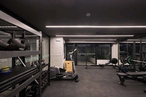 Ein Fitnessstudio mit Trainingsgeräten, Gewichtsständern und Laufband.