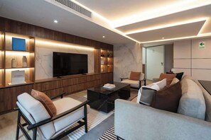 Ein modernes Wohnzimmer mit Flachbildfernseher, Sofas, Couchtisch und Einbauschränken mit Dekorationselementen.