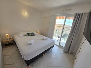 A hotel bedroom with a bed, bedside lamps, a door, and a view of the outside. - Villa Norma by Interhome (Cannes)