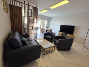 A modern living room with a sofa set, a coffee table, a TV, and a partition with vertical slats. - Villa Norma by Interhome (Cannes)