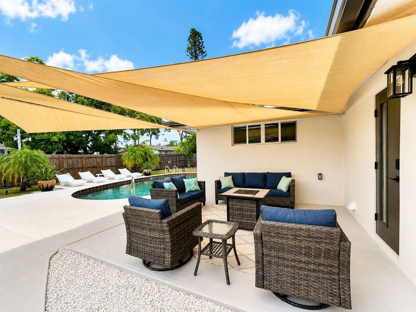 Un espace extérieur aménagé avec des meubles en osier, une piscine et une vue sur le jardin arrière.