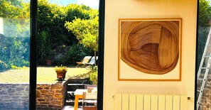 Ein Zimmer mit Blick auf einen Garten, ein hölzernes Kunstwerk an der Wand und eine Steinwand.