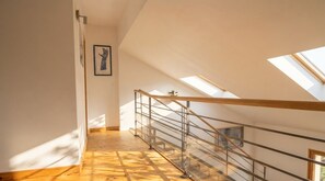 Eine Treppe mit Glasgeländer, Holzboden und Oberlichtern.