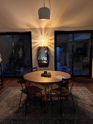 A dining area with a round table, chairs, a rug, and a pendant light. - The Enclosed Garden of Cancale (Cancale)