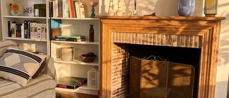 A cozy living room with a fireplace, bookshelves, a sofa, and a coffee table.