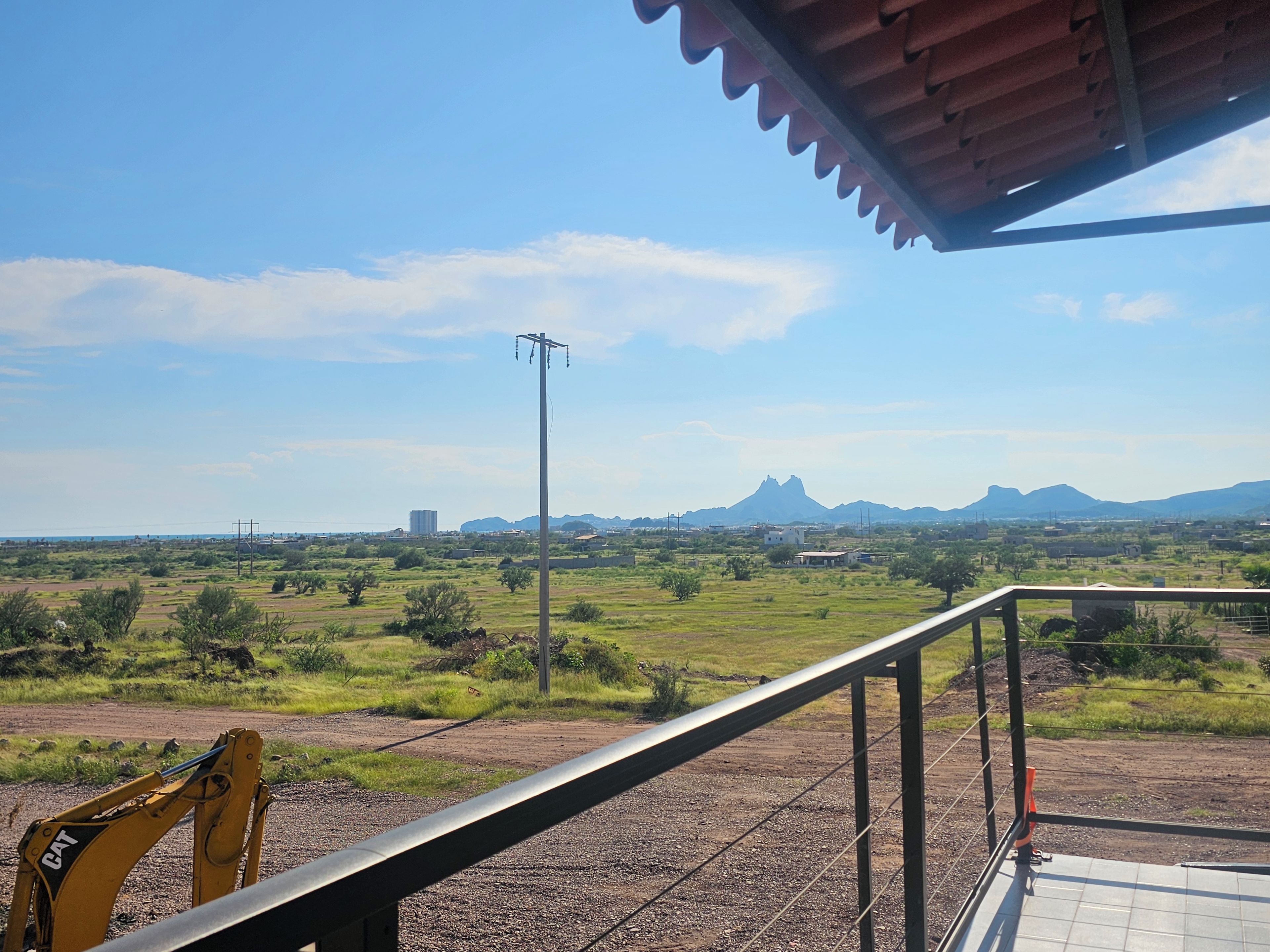A view from a covered balcony overlooking a rural landscape with a distant mountain range.