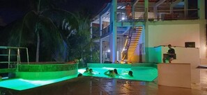 An indoor swimming pool with a staircase leading to an upper level, surrounded by palm trees. - I Wanna Palomino (Palomino)