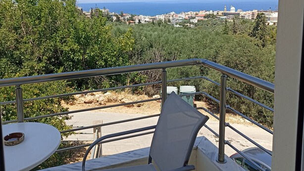 A balcony with a view of the sea, a table, and a chair. - studio staring at sunset 1-bedroom studio in beautiful Χανια with AC (ΧΑΝΙΑ)
