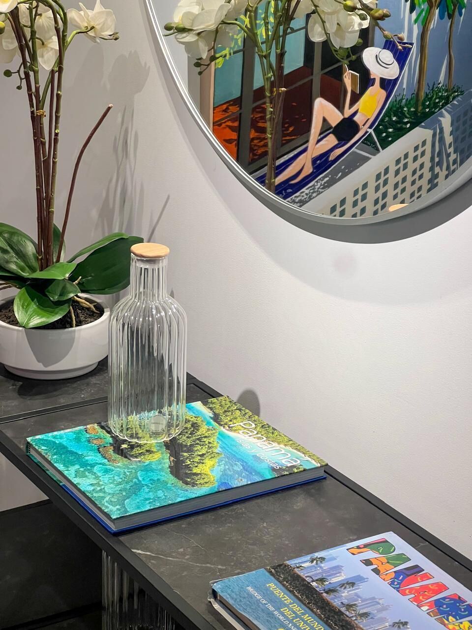A table with a glass bottle, a potted plant, and two books.