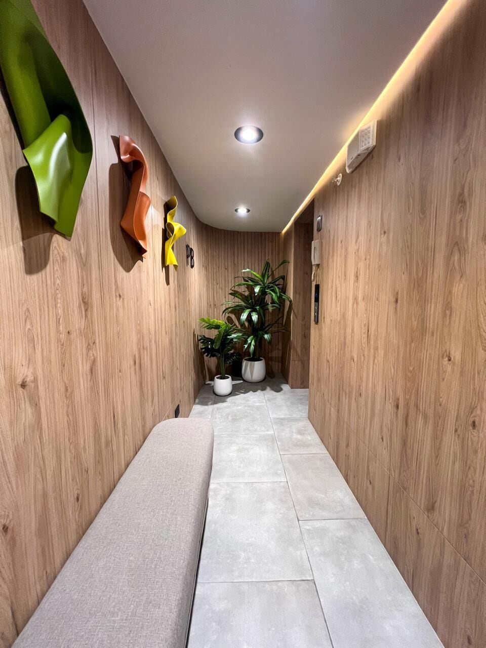 A hallway with wooden walls, a bench, and potted plants.