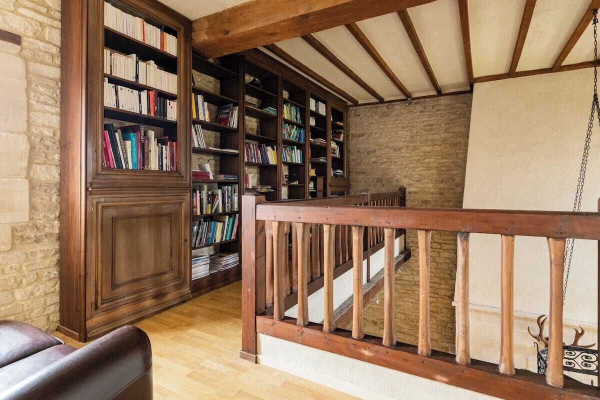 Eine Bibliothek mit Bücherregalen, einer Holztreppe und einem Ledersessel.
