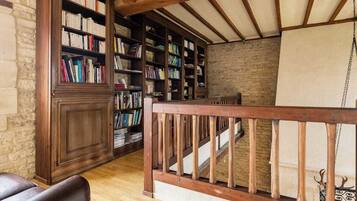 Eine Bibliothek mit Bücherregalen, einer Holztreppe und einem Ledersessel.