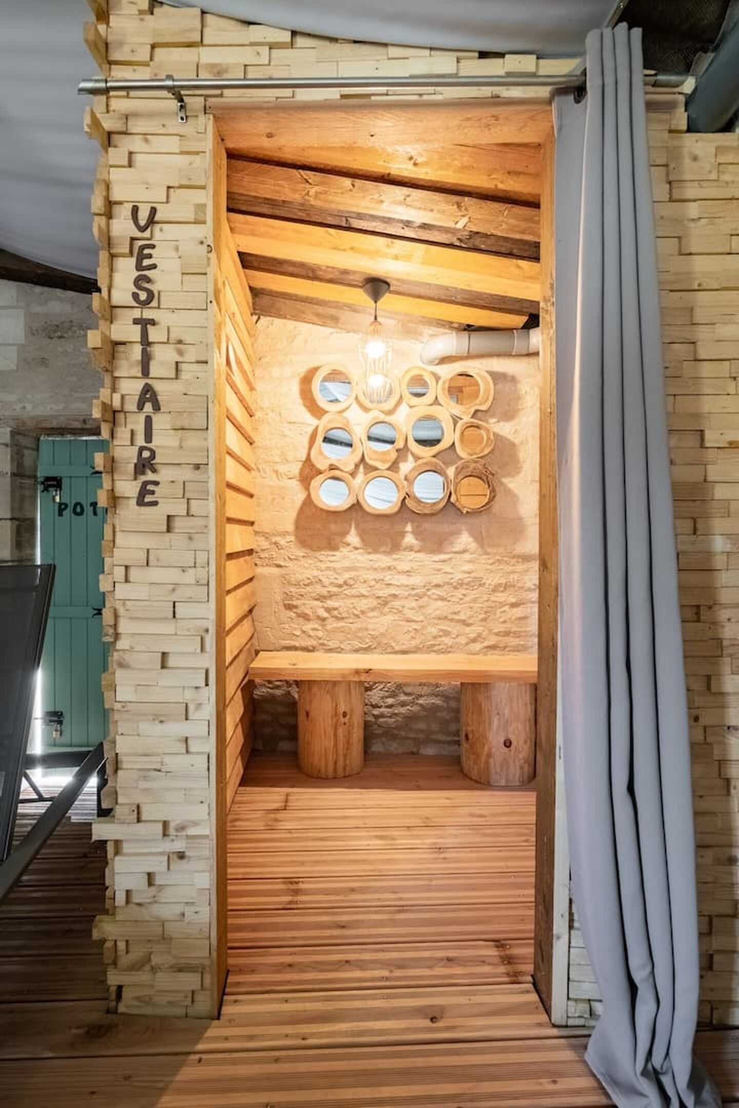 Eine Holzsauna mit einer wandmontierten, kreisrunden Spiegelanordnung und einer hölzernen Sitzbank.
