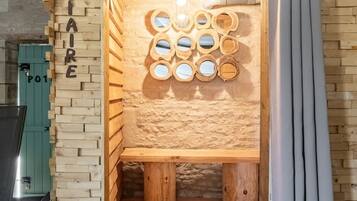 Eine Holzsauna mit einer wandmontierten, kreisrunden Spiegelanordnung und einer hölzernen Sitzbank.