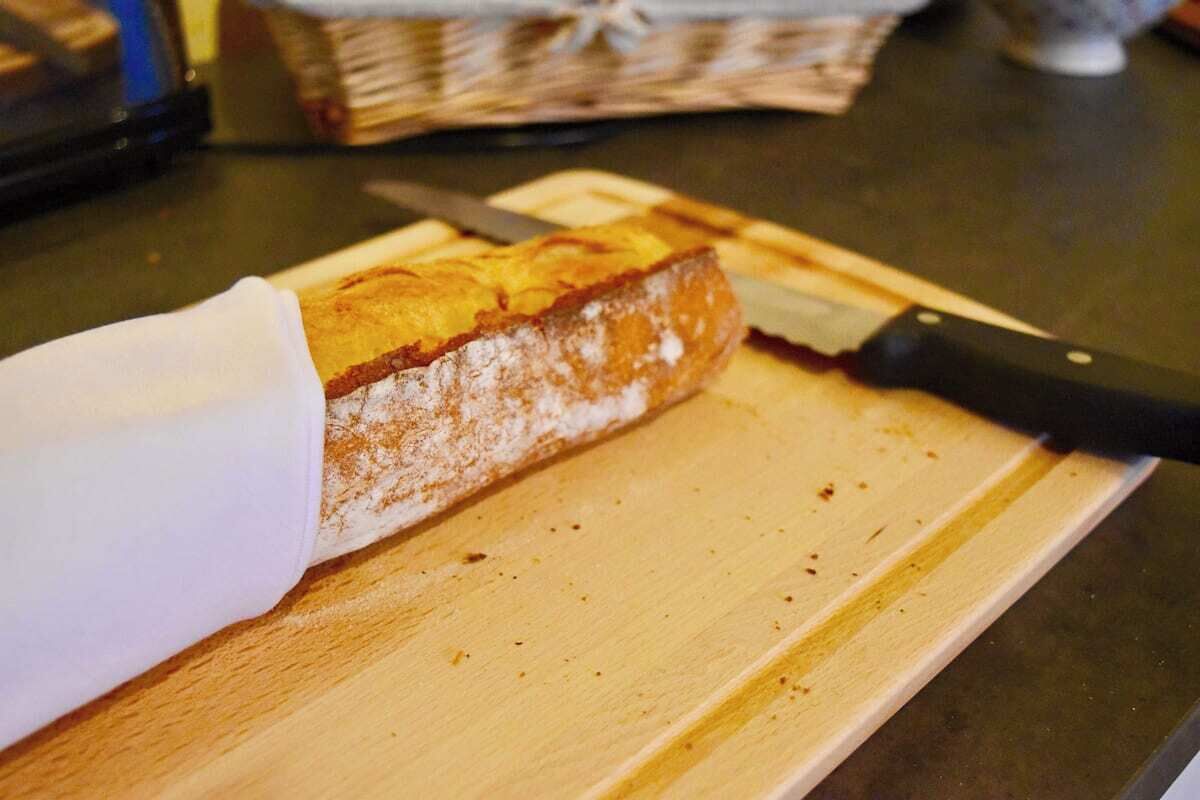 Een brood wordt op een houten snijplank in plakken gesneden.
