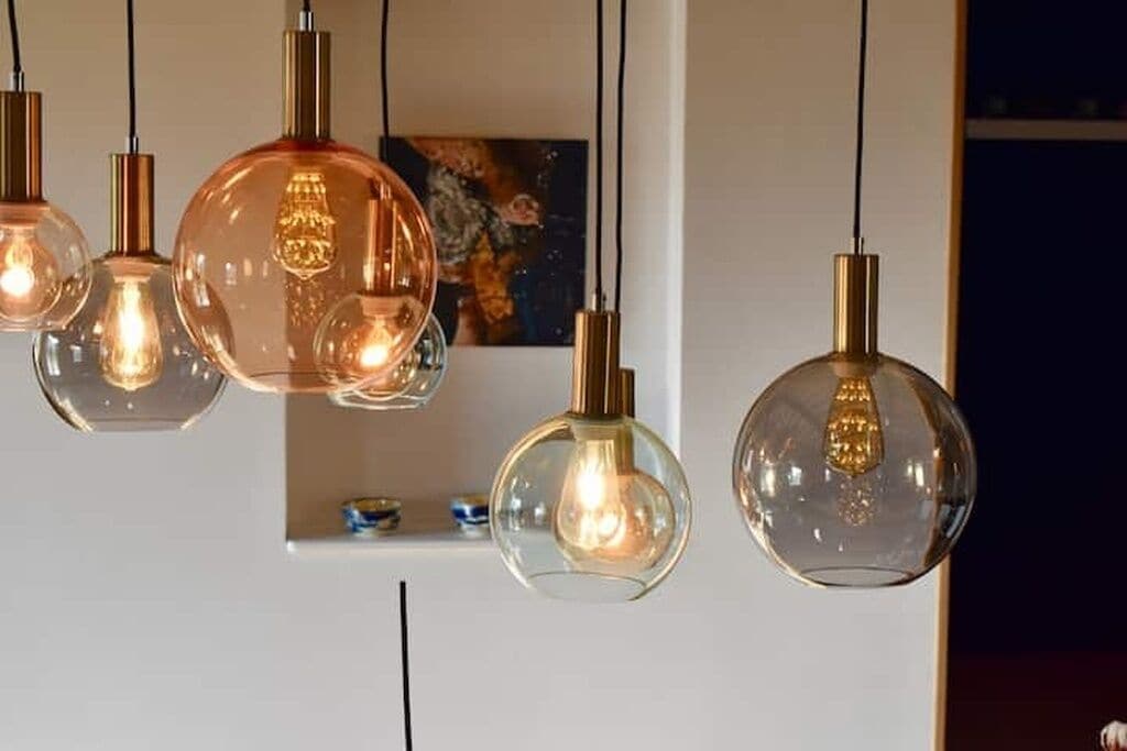 Een reeks hanglampen met heldere glazen kappen en koperkleurige schachten.