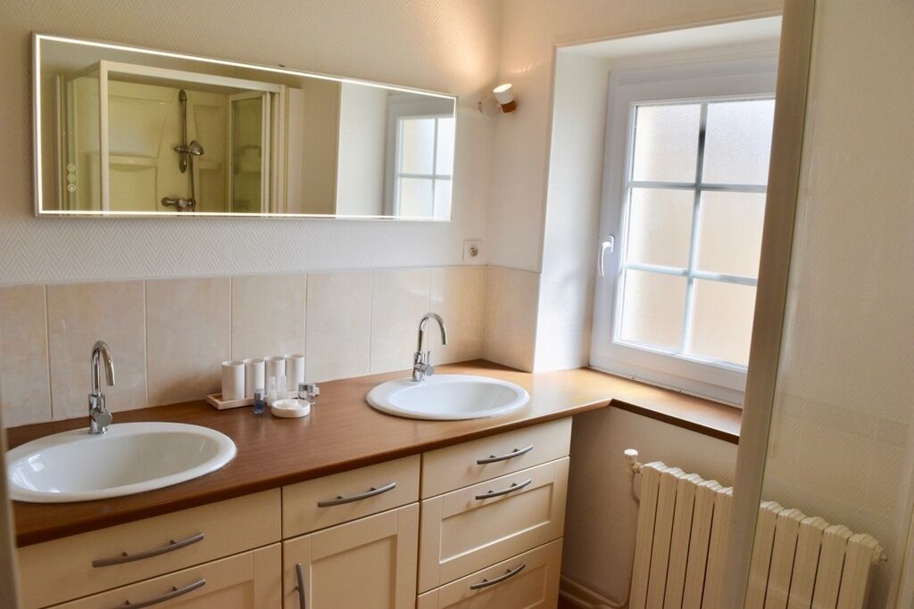 Un baño con dos lavamanos, un espejo y una ventana.