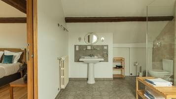 Une chambre à coucher comprenant un lit, une table de chevet et un radiateur, ainsi qu’une salle de bain avec un lavabo, un miroir et des toilettes.