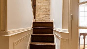 A staircase with wooden steps leading to a stone wall, white walls, and a door with a window.