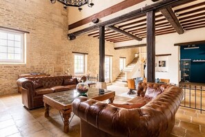 A spacious room with a leather sofa, a coffee table, and a staircase leading to another level.