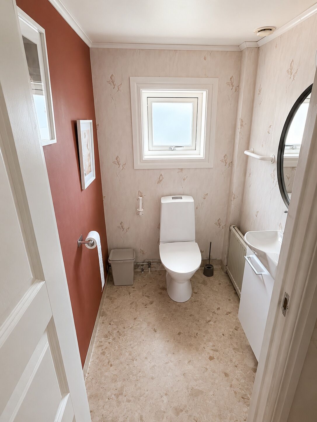 A small bathroom with a toilet, a sink, a window, and a door.