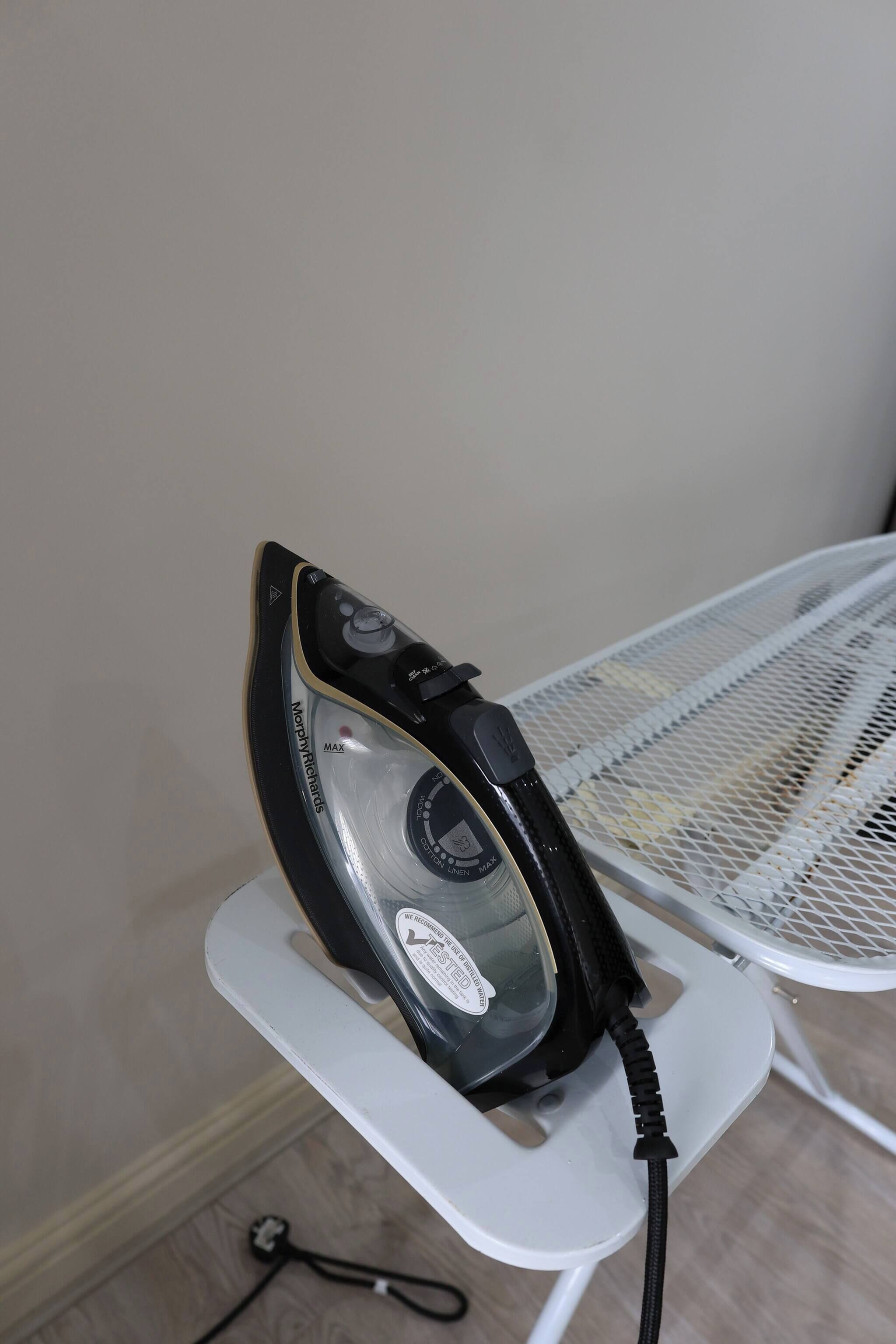 A portable iron on a white stand.