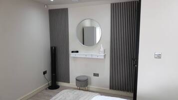 A bedroom with a bed, a round mirror, a small stool, and a radiator.