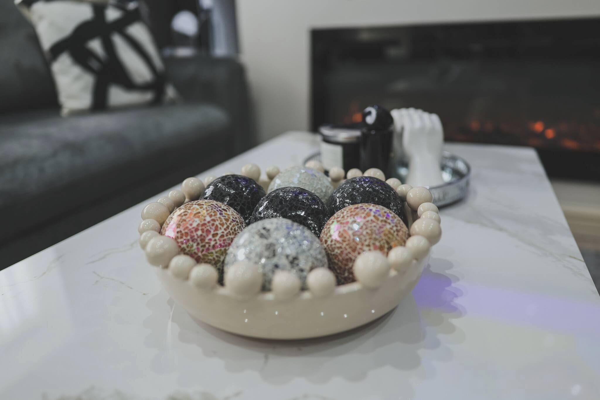 A bowl of decorative eggs on a marble table.
