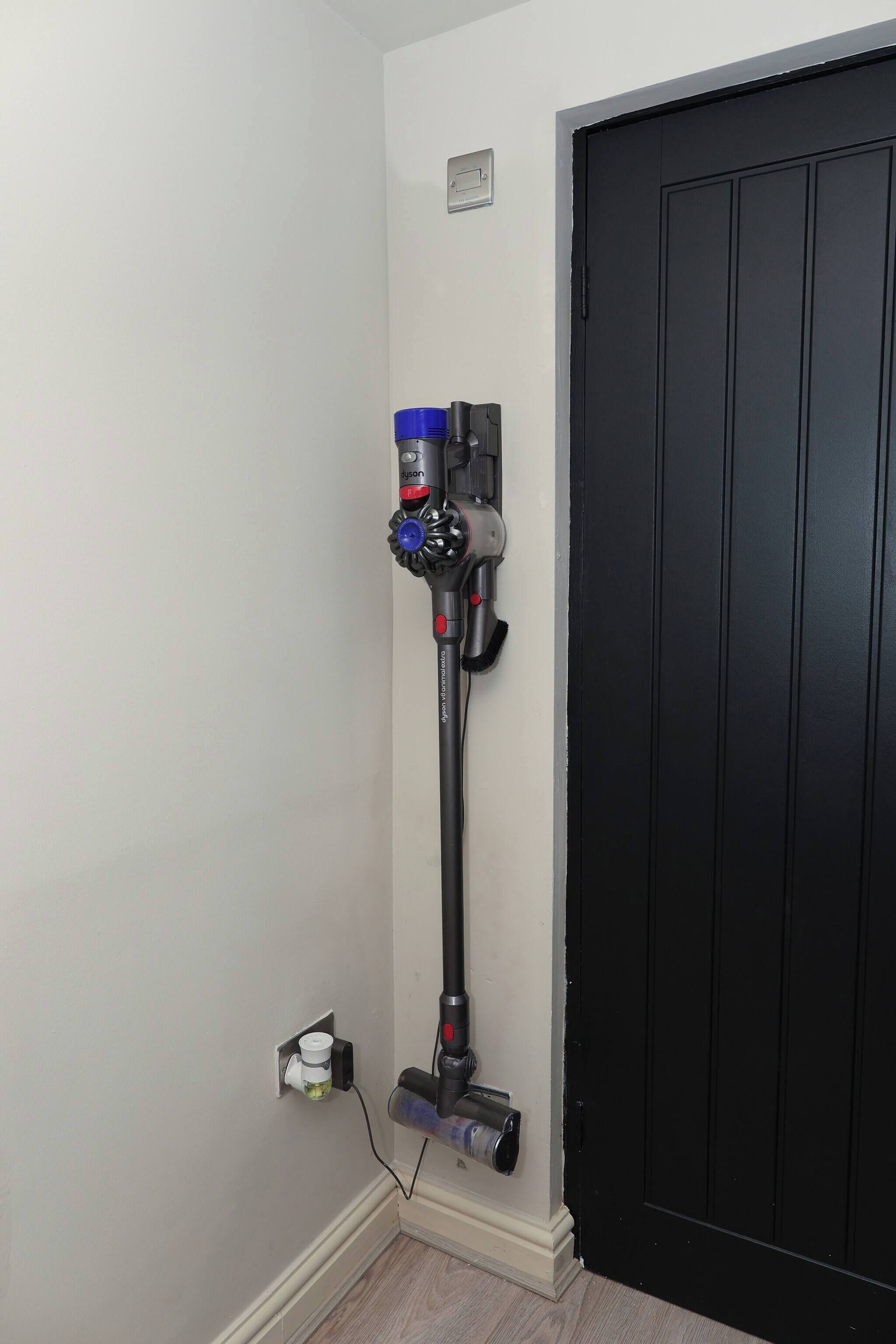 Aspirador de pó fixado na parede perto de uma porta.