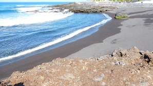 A beach with rocky foreground, a sandy shoreline, and a clear view of the ocean. - El Navio (Guia de Isora)