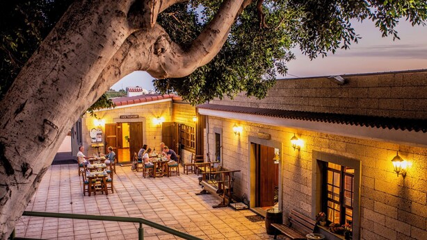 An outdoor dining area with tables and chairs, a staircase, and a building with a sign that reads 'RESTAURANT.' - El Navio (Guia de Isora)