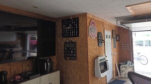 A room with a large flat-screen TV, a dartboard, a clock, and a fan. - Enjoyable 2-bedroom house with boat dock across from Cranberrys. (Huntsville)