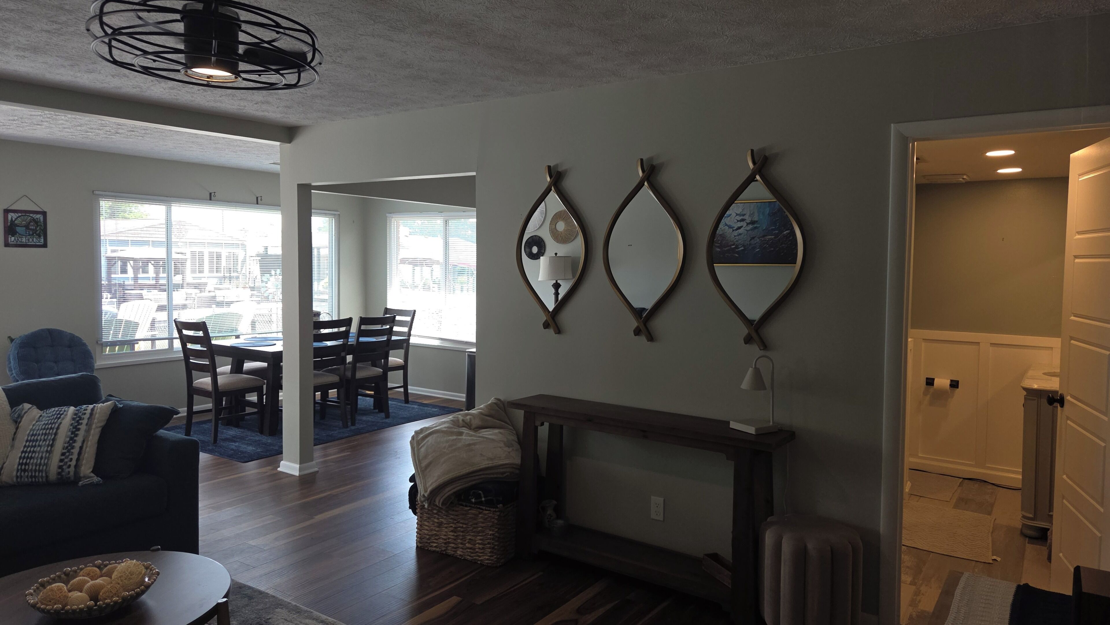 A living room with a fireplace, dining area, and large windows.