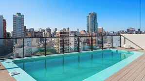 Una piscina en la azotea con vistas a la ciudad, rodeada de edificios altos.