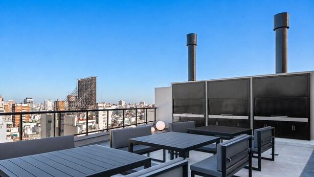 Una terraza en la azotea con mobiliario exterior, un televisor de pantalla plana grande y dos chimeneas.