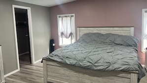 Un dormitorio con una cama, un armario y una puerta que da a otra habitación.