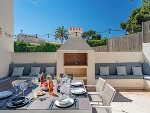 An outdoor dining area with a built-in grill, seating, and a view of the neighborhood. - Vacation home Bartok by Interhome (Jávea)