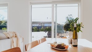 Un comedor con una mesa dispuesta para dos personas, una botella de vino y un plato de comida.