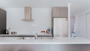 Una cocina moderna con un lavamanos de acero inoxidable, horno empotrado y salpicadero de azulejos blancos.