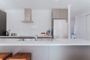 A modern kitchen with a stainless steel sink, a built-in oven, and a white tiled backsplash. - Brand new, near the lake, sleeps 8! (Rotorua)