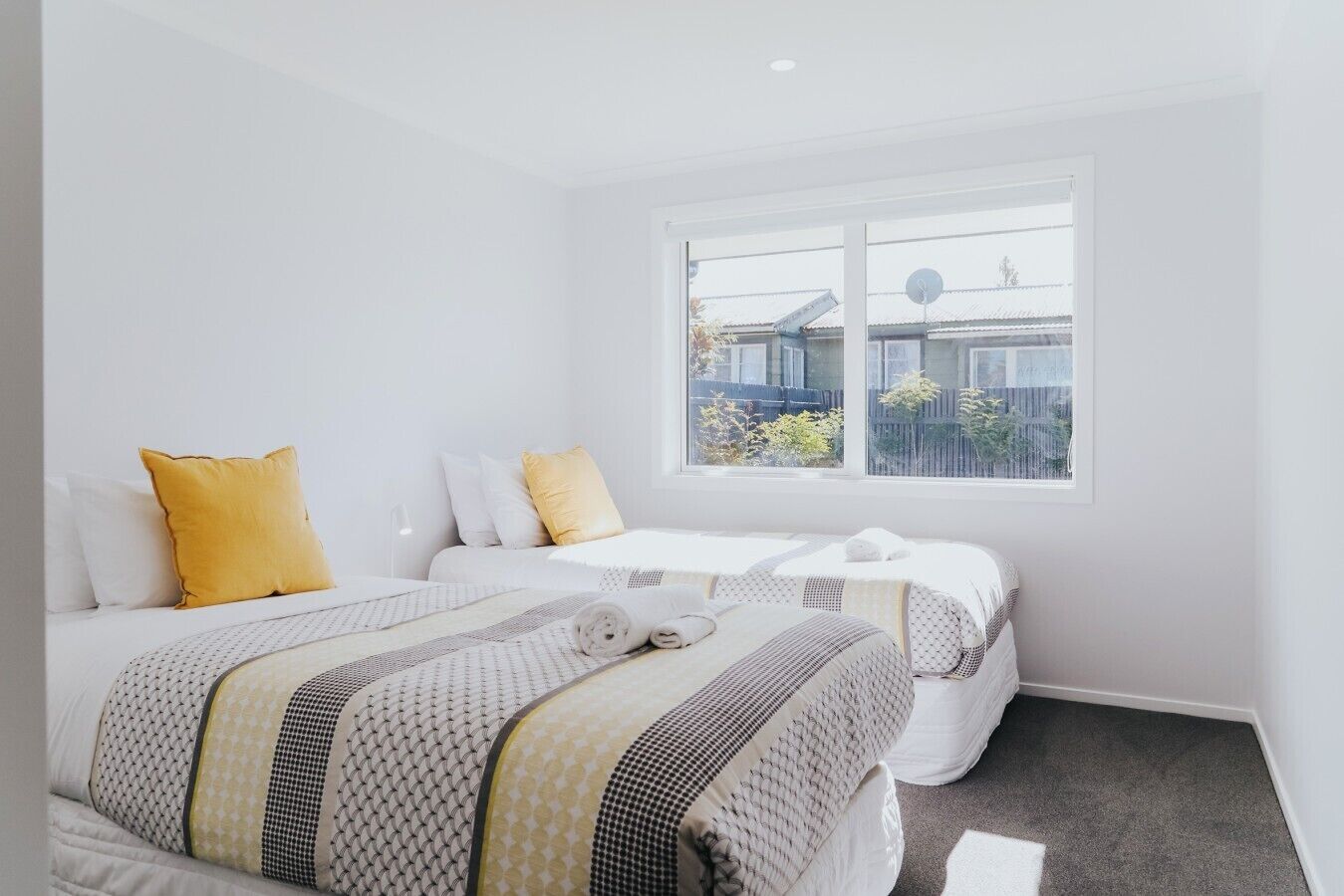 A hotel room with two beds, a large window, and a view of the outside.