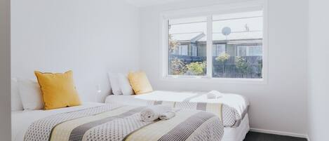 A hotel room with two beds, a large window, and a view of the outside.