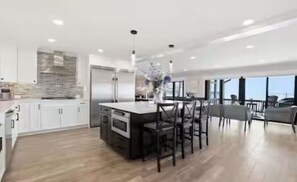 Una cocina moderna con una isla central, muebles blancos y vistas al exterior.