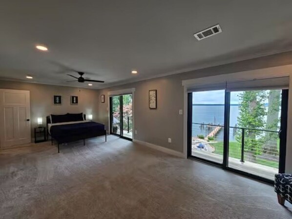 A spacious bedroom with a bed, a ceiling fan, and a view through large sliding glass doors.