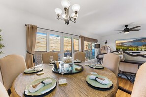 A dining area with a round table set for four, a chandelier, and a view of a vineyard through large windows. - Luxury French-Inspired Retreat • Private Terrace (Kelowna)