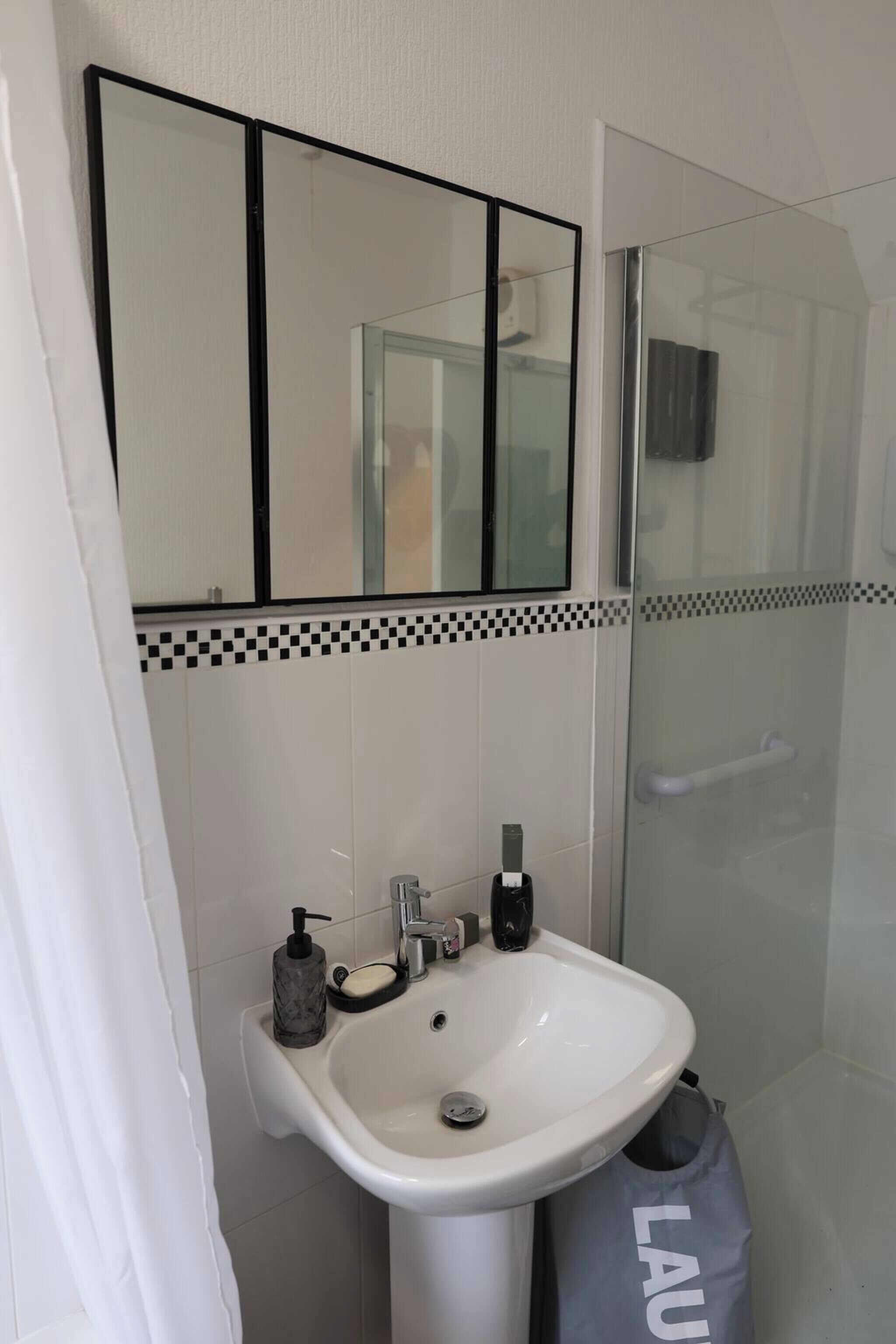 A bathroom with a white sink, a mirror, and a shower.