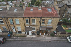 Un edificio residencial de dos pisos con techo de tejas rojas, varias ventanas y una entrada principal.