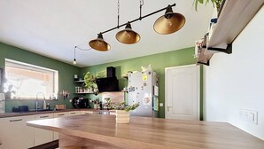 Una cucina con un'isola in legno, sgabelli da bar, un frigorifero e una finestra.