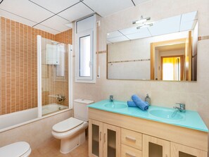 Ein Badezimmer mit Toilette, Waschbecken, Spiegel und Duschkabine.
