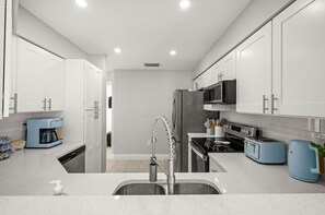 Eine moderne Küche mit weißen Schränken, Edelstahlgeräten und einem blauen Toaster.